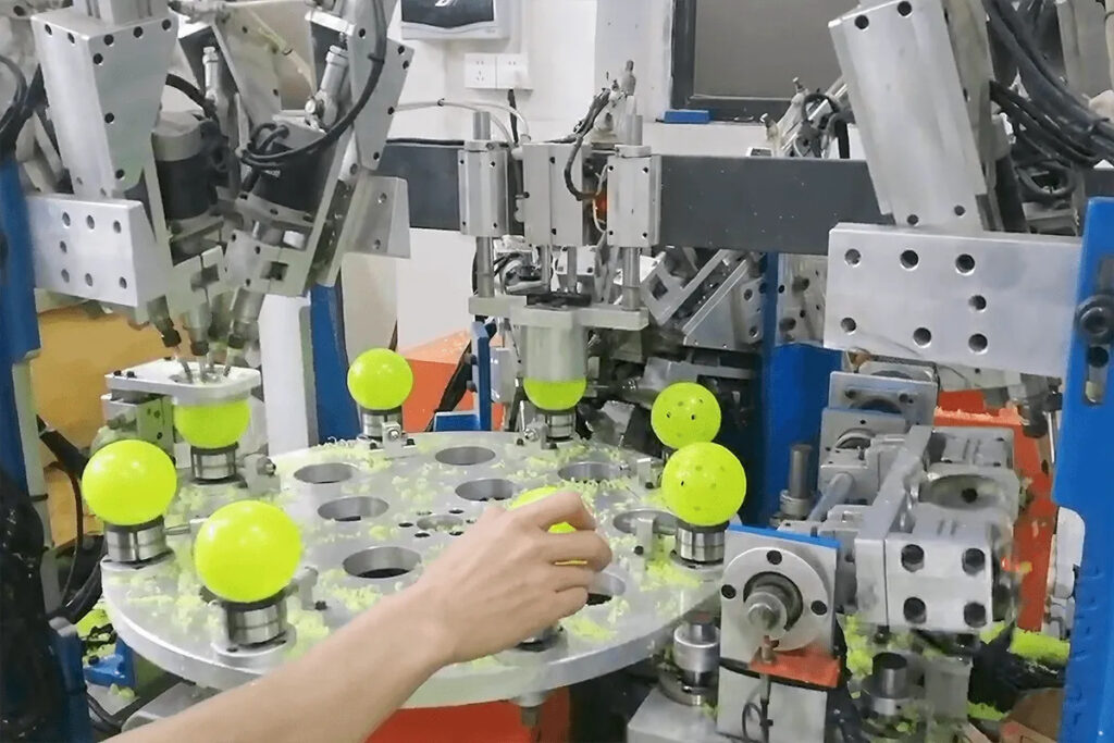 Automated machine manufacturing pickleballs with precision drilling