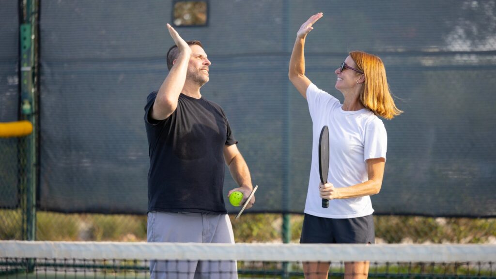 Pickleball doubles teammates celebrating a win
