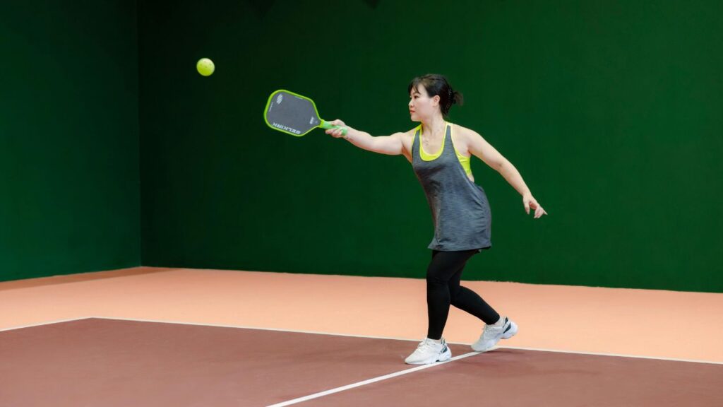 Beginner player reaching for a forehand with a pickleball paddle