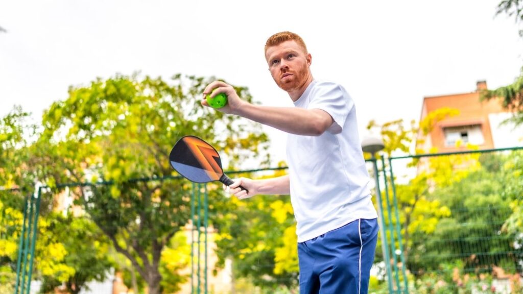 Male Player Serving pickleball on an outdoor court