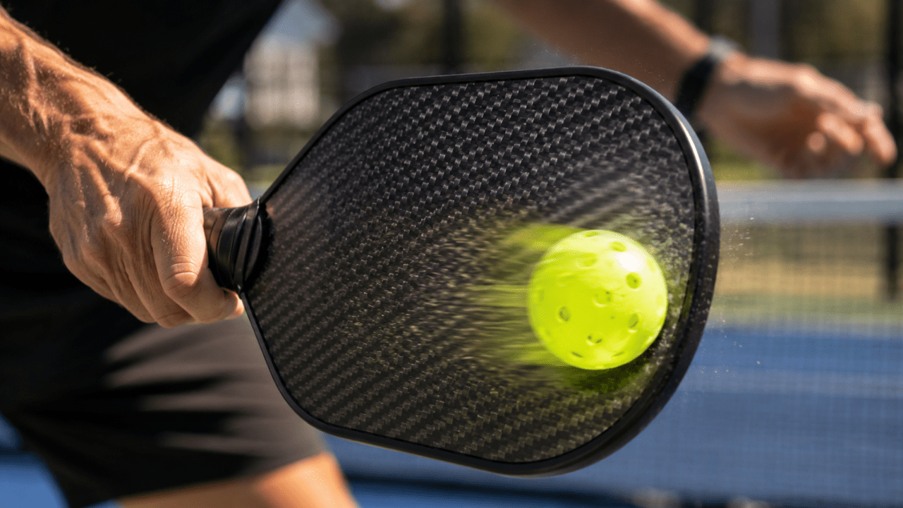 Carbon fiber pickleball paddle generating topspin during gameplay